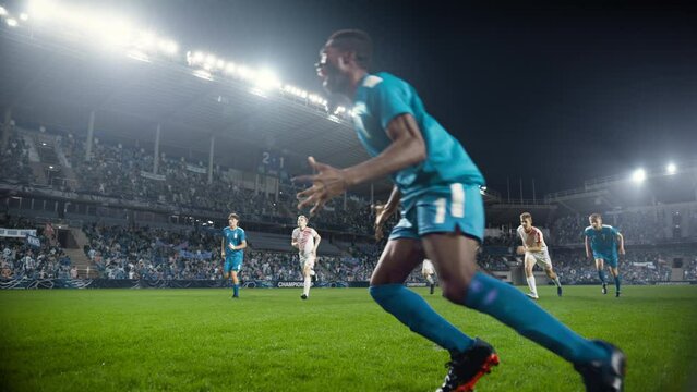 Football Championship: Blue Team Forward Hits the Ball and Scores Perfect Goal in Slow Motion. Goalkeeper Jumps and Fails to Catch, Protect Goals. Crowd of Fans Cheers. Playback in Cinematic Front