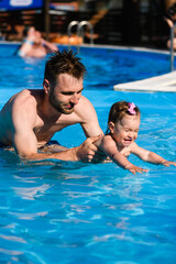 Father teach toddler girl how to swim