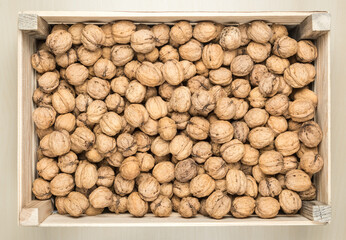 Wooden box filled with whole walnuts, view from above