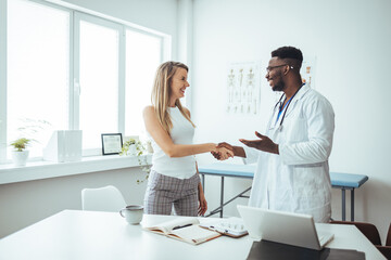 Confident Doctor shaking hands with patients talk in the hospital. Men demonstrating welcome and friendly gesture. Medical treatment and health care concept. Blurred background