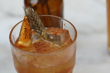 Closeup of a cocktail with a rum base, orange and dried wheat with spices