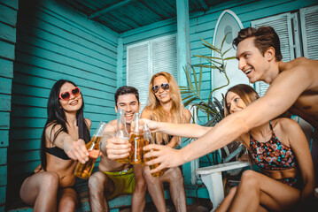 Group of five friends celebrating in their summer beach house. Party people spending a vacation day in their bungalow in a tropical village in front the ocean