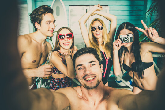 Group of five friends celebrating in their summer beach house. Party people spending a vacation day in their bungalow in a tropical village in front the ocean