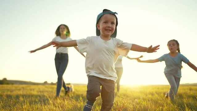 Happy family concept.Child run hand to the sides in park.Child play with dog in field on green grass.Family games of friend at sunset.Dream kid in summer in park.Family jogging in green grass with dog