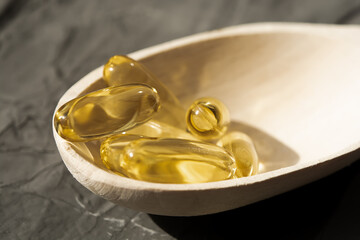 Omega 3 vitamins in a wooden spoon lie on a gray background, sports, vitamins, healthy lifestyle, dietary supplements, vitamin therapy, sports supplements