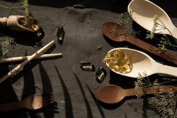 Wooden utensils on the table, spoons, forks, scoops for food, omega 3 vitamins lie in a wooden spoon, sports, vitamins, healthy lifestyle, dietary supplements, vitamin therapy, sports supplements