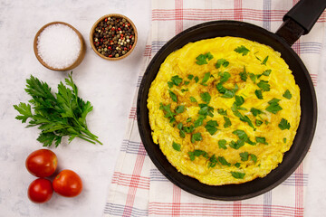 Homemade egg omelette with tomatoes and parsley on a gray background