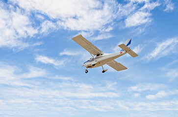 Fototapeta na wymiar Single engine ultralight plane flying in the blue sky with white clouds