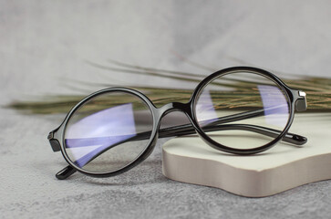 Stylish round glasses for vision on a beige podium, close-up