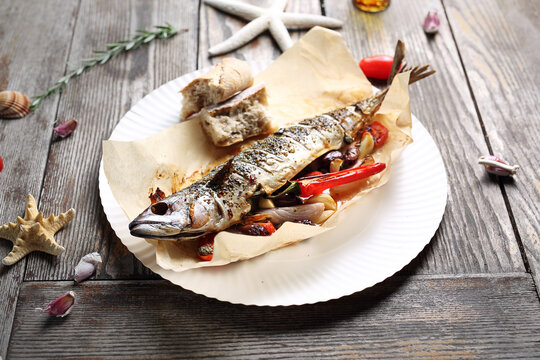 Whole, baked mackerel, served with vegetables and bread, on a plate, top view. Roasted fish on a parchment paper.