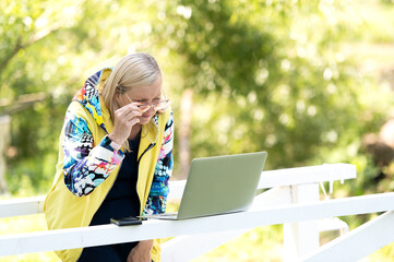 Excited desperate business woman standing in city park and looking at laptop screen