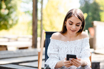 Fototapeta premium Young pretty woman working watching smartphone in modern park street