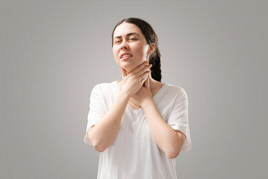 Angina and chronic tonsillitis. Portrait of a suffering young woman holding her throat. The concept of health and cold insurance