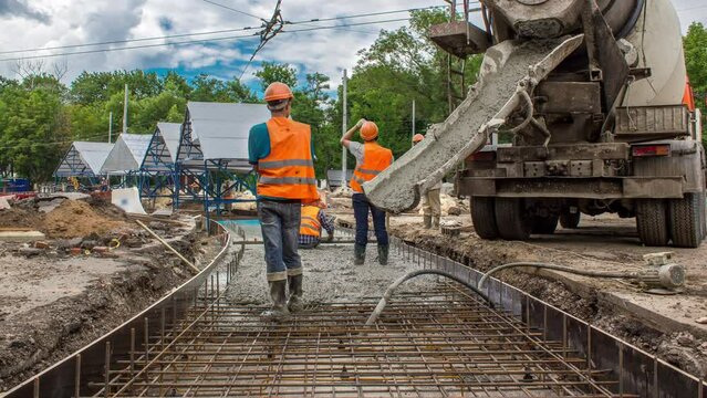 Concrete works in metal reinforcement for road construction with many workers in uniform, excavators and mixer machine timelapse. Reconstruction of tram tracks