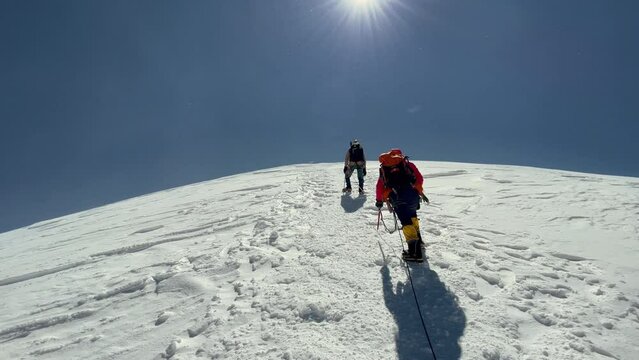 4K footage of two alpinists in winter climbing clothes walking slowly together towards top of mountain. Last steps before Kazbek (Kazbegi) summit 5054m. Climbing, alpinism, winter sports, extreme spor