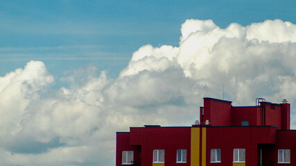 Fluffy clouds over the red residental building.