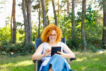 A woman sitting in nature and browsing internet and purchasing for the Black Friday
