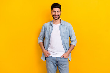 Photo of young positive guy confidently looking camera sure best worker hands pockets isolated on yellow color background