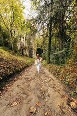 Fototapeta premium vertical photo of a woman walking along a path surrounded by trees