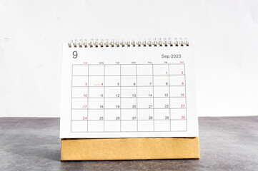 September 2023 Desktop calendar for planners and reminders on a wooden table on a white background.