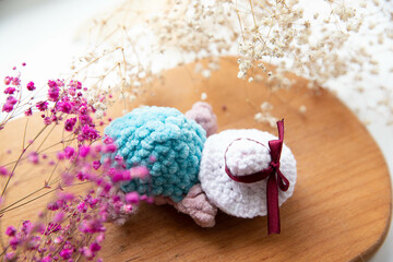 beautiful knitted turtle with a hat on a background of flowers