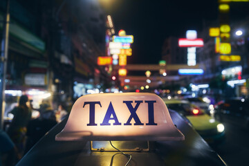 Illuminated taxi sign on roof of tuk tuk. Night traffic in Chinatown in Bangkok, Thailand,.