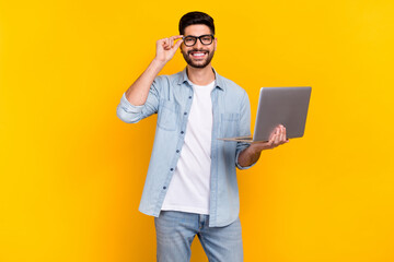 Photo of cheerful latin young guy touch eyewear visit remote work conference wear stylish denim look isolated on yellow color background