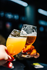 Two friends hands toasting with glasses of light beer at the pub or bar