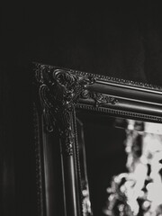 Vertical greyscale shot of a chandelier reflected in a mirror