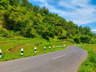 a highway under the hills against the background of a bright blue sky