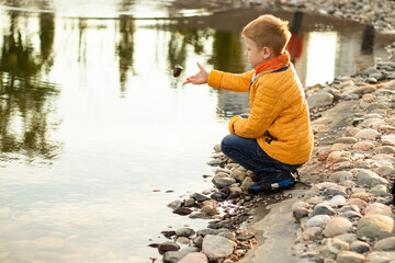 Portrait of red-haired teenager boy in yellow clothes near lake in city park at sunset. Child...