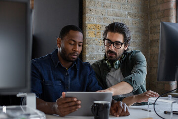 Coworkers working together on a presentation on a digital tablet