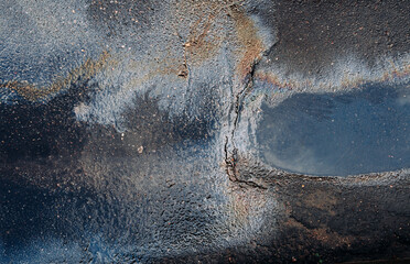 Dirty multi-colored stain from engine oil on asphalt. Environmental pollution concept. Abstract texture multicolored