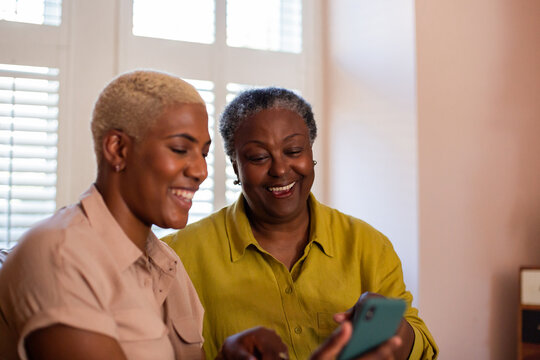 Senior African American woman looking at photos on a smartphone with her daughter