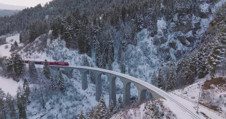 Landwasser Viaduct world heritage sight with luxury Glacier and Bernina express in Swiss Alps snow winter scenery. Aerial Drone shot red train passing through famous mountain in Filisur, Switzerland. - Powered by Adobe