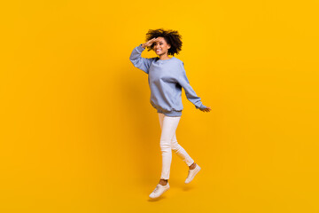 Fototapeta na wymiar Full length profile portrait of active pretty girl jumping hand touch forehead look empty space isolated on yellow color background
