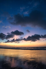 Fototapeta na wymiar Beautiful sunset sunrise at the beach with dramatic clouds in the blue purple yellow sky over the sea - Bali