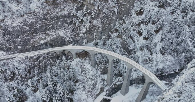 Aerial drone view Landwasser Viaduct world heritage sightseeing with luxury Glacier express train in Swiss Alps snow winter day scenery. Panoramic scenic railway landscape tourism in Switzerland.