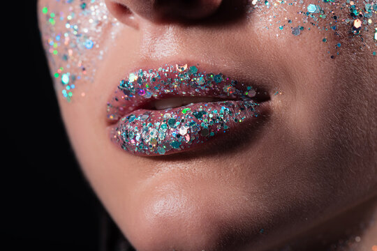 cropped view of young woman with sparking glitter on lips isolated on black.