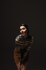 curious young woman in striped turtleneck with skirt posing isolated on black.