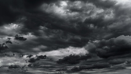 dark dramatic sky with black stormy clouds before rain or snow as abstract background, extreme weather, the sun shines through the clouds, high contrast photo