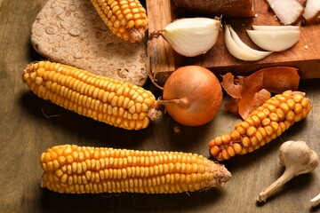 still life of food in a rural style on a dark wood background, corn and garlic, concept of fresh vegetables and healthy food