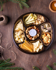 Cheese plate with honey, nuts on brown table, flat lay. Space for text