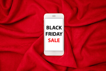 Mobile phone with black friday sale text on red fabric background, technology and shopping from home 