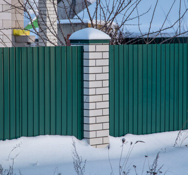 Brick pillar on the fence in the snow.