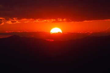 Red light from sunset behind cloudy sky.