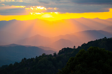 Dramatic sunset over mountain ranges with orange sunlight.