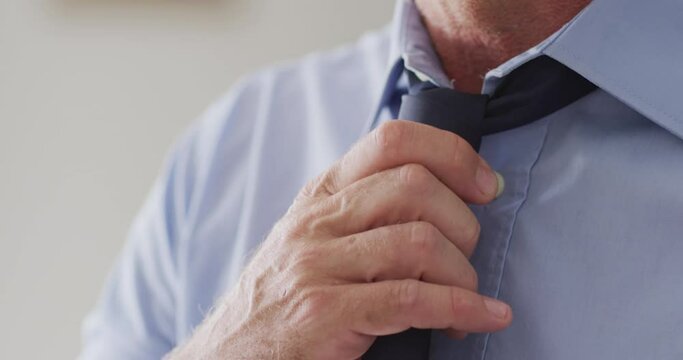 Happy caucasian man standing in living room and wearing tie
