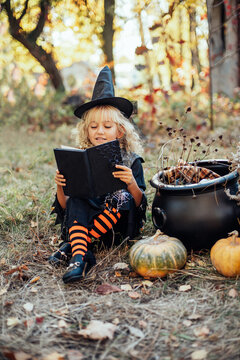 Beautiful girl witch. little girl in which costume celebrate Halloween outdoor and have fun. Kids trick or treating. girl witch with magic Book of spells.