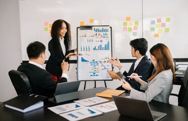 Female entrepreneur smiling while delivering a presentation to team in office boardroom. Businesswoman having meeting with colleagues with coworkers